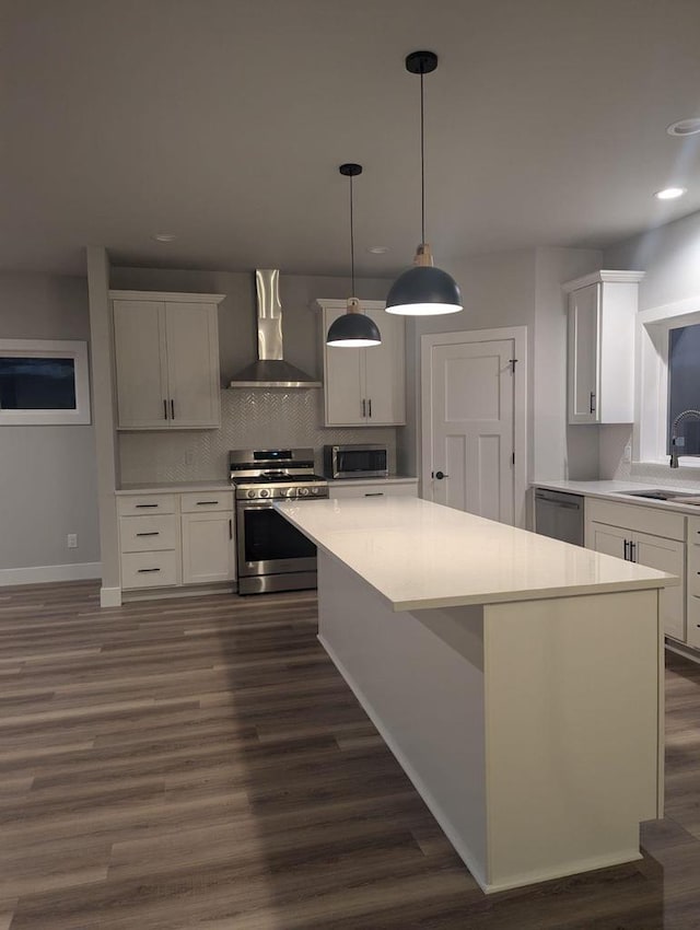 kitchen featuring a sink, stainless steel appliances, wall chimney exhaust hood, and light countertops