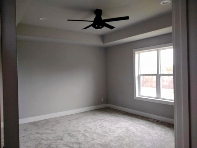 unfurnished room featuring light colored carpet, ceiling fan, visible vents, and baseboards