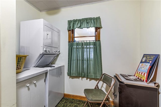 laundry area featuring stacked washer and dryer, ornamental molding, and cabinets