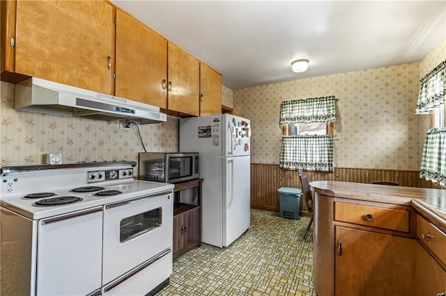 kitchen featuring white appliances and wood walls