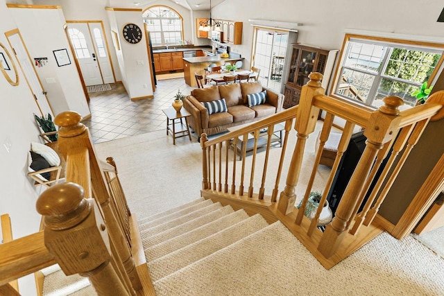 stairs featuring tile patterned floors, a healthy amount of sunlight, baseboards, and lofted ceiling