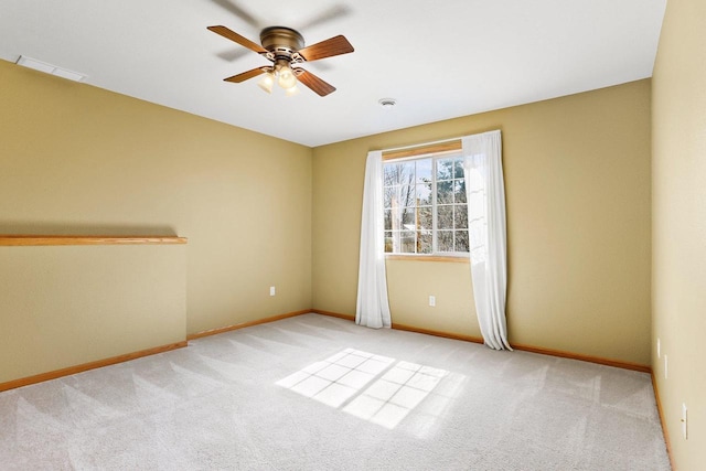 spare room featuring light carpet, visible vents, ceiling fan, and baseboards