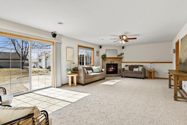 living room featuring baseboards, light carpet, a brick fireplace, and ceiling fan