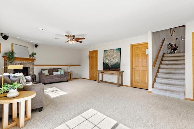 carpeted living area featuring stairway, baseboards, a brick fireplace, and ceiling fan