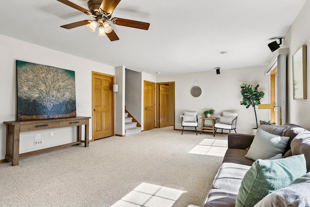 living room with baseboards, carpet, ceiling fan, and stairs