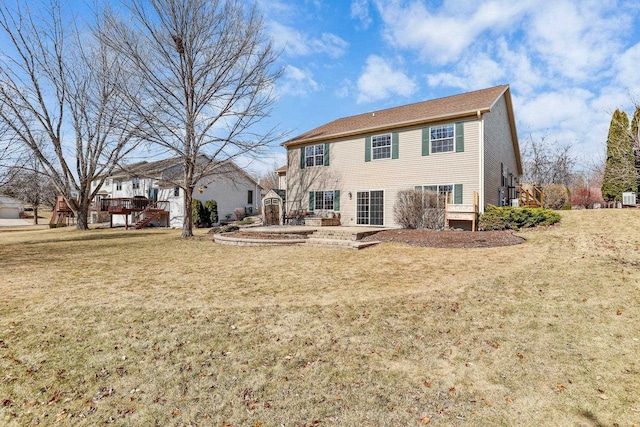 rear view of house with a deck, a patio area, and a lawn