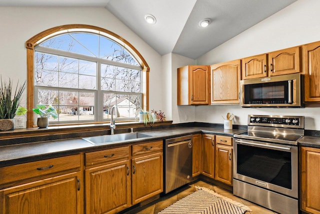 kitchen featuring a sink, stainless steel appliances, lofted ceiling, and dark countertops