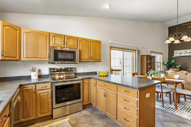 kitchen featuring dark countertops, appliances with stainless steel finishes, a peninsula, and vaulted ceiling