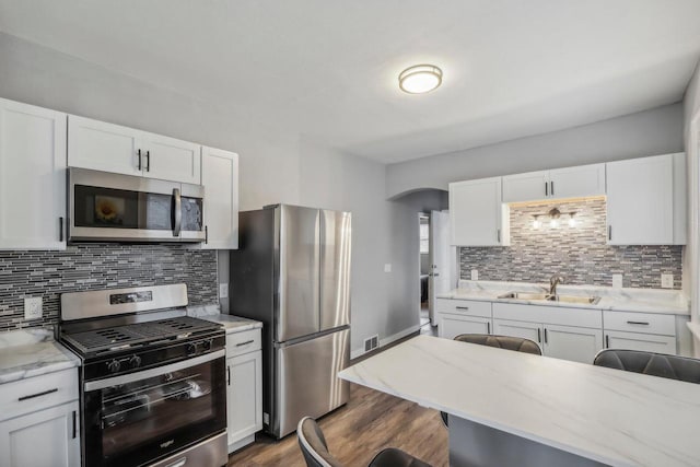 kitchen featuring white cabinetry, appliances with stainless steel finishes, sink, and a breakfast bar area