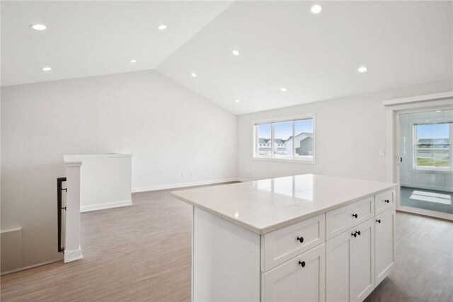 kitchen featuring plenty of natural light, a center island, white cabinets, and vaulted ceiling