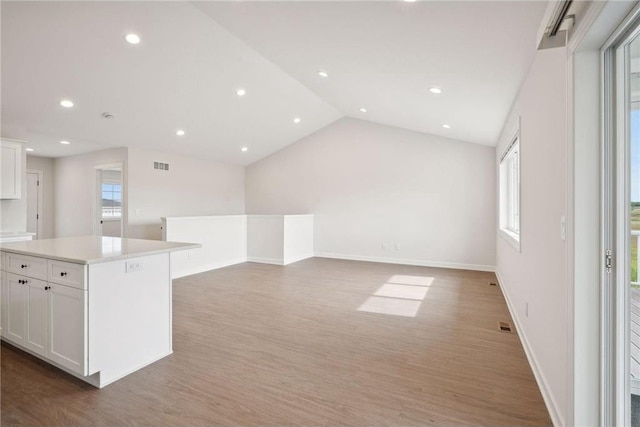 kitchen featuring hardwood / wood-style flooring, white cabinetry, a kitchen island, and lofted ceiling