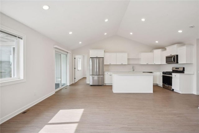 kitchen with stainless steel appliances, a center island, light wood-type flooring, and white cabinets