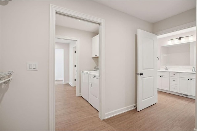 interior space with sink, washing machine and dryer, and light wood-type flooring