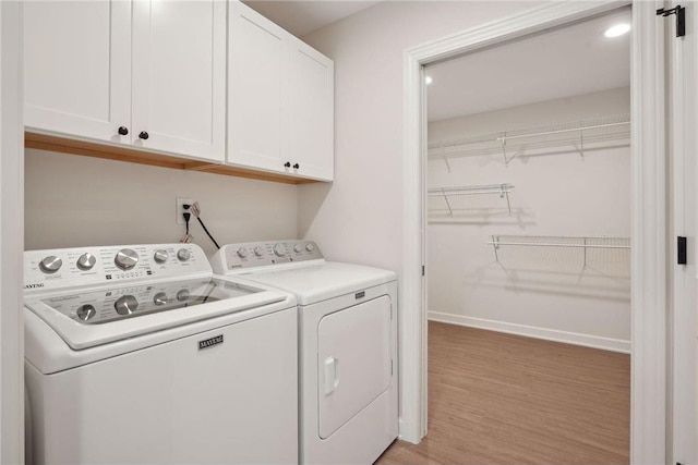 washroom with cabinets, washing machine and dryer, and light wood-type flooring