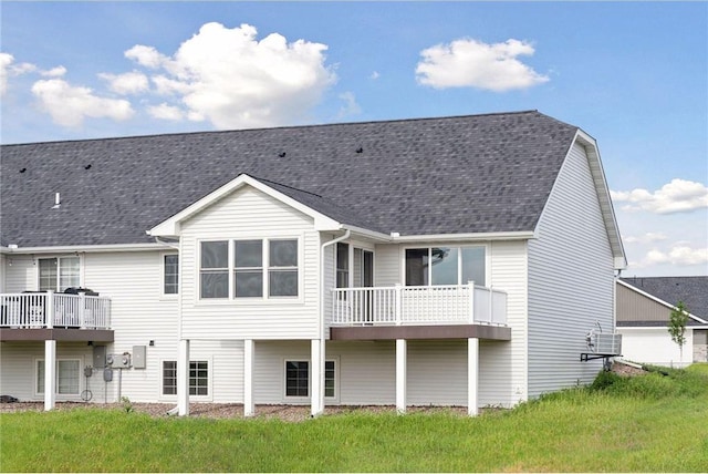 rear view of house featuring a balcony and a yard