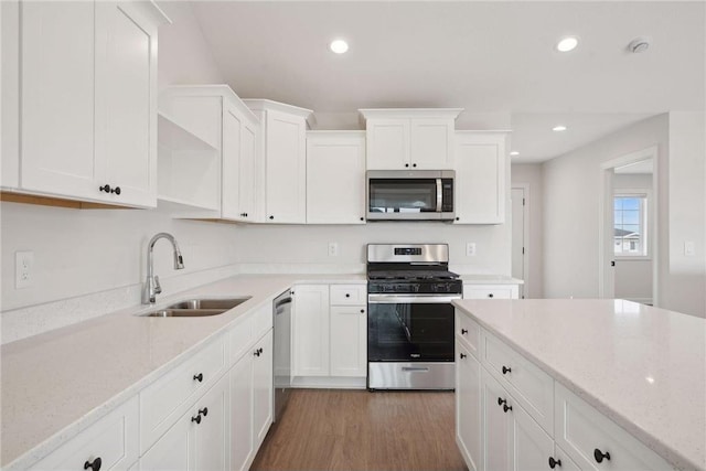 kitchen with sink, stainless steel appliances, light stone counters, white cabinets, and dark hardwood / wood-style flooring