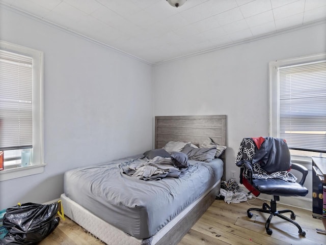 bedroom featuring ornamental molding, light hardwood / wood-style floors, and multiple windows