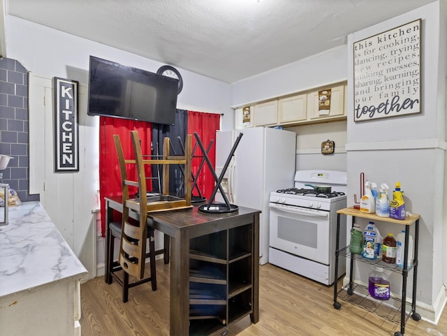 kitchen featuring white appliances, light hardwood / wood-style floors, a textured ceiling, and light brown cabinets