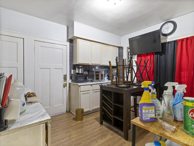 kitchen featuring decorative backsplash, light hardwood / wood-style flooring, a textured ceiling, and white cabinets