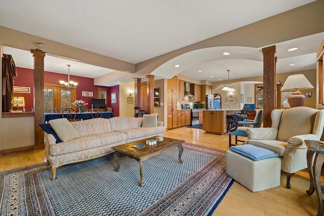 living room featuring an inviting chandelier, light hardwood / wood-style flooring, and ornate columns