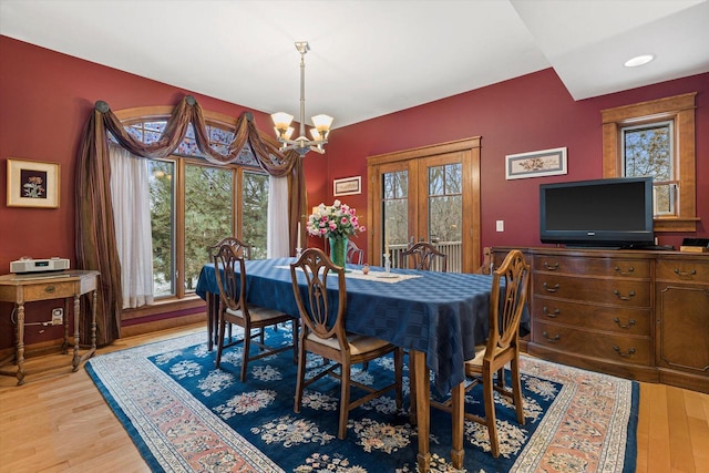 dining room featuring an inviting chandelier, light hardwood / wood-style flooring, and french doors