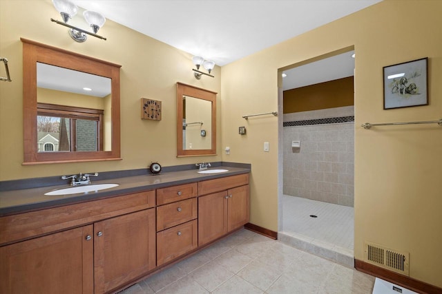 bathroom featuring tiled shower, vanity, and tile patterned flooring