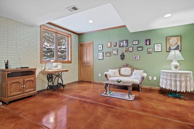 living area with concrete flooring, ornamental molding, and brick wall