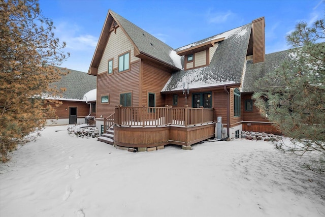 snow covered back of property featuring a wooden deck