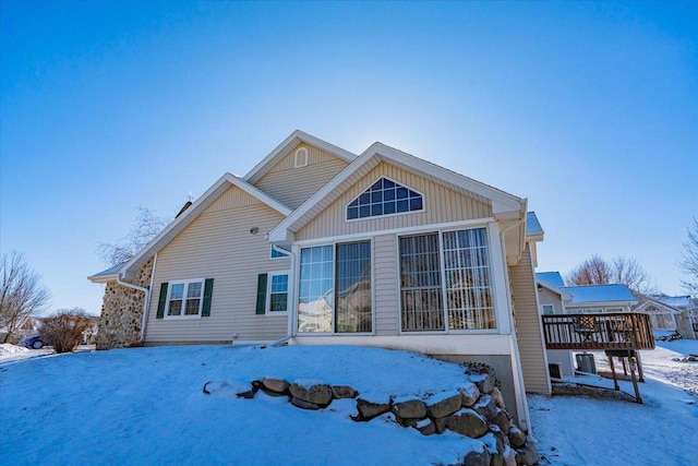 snow covered house featuring a wooden deck