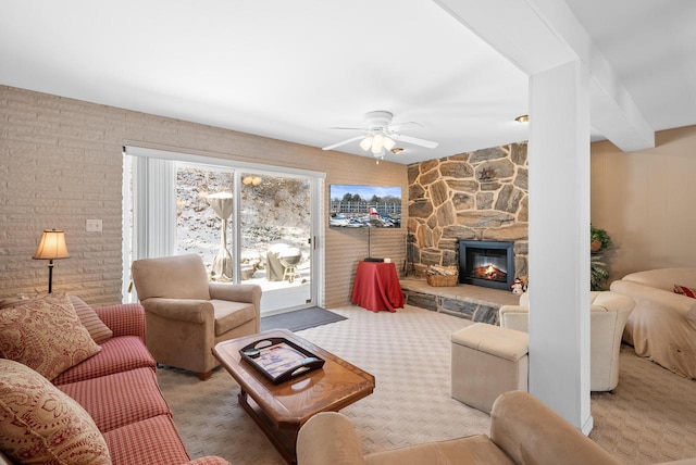 living room with ceiling fan, a stone fireplace, and light carpet