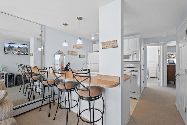 kitchen with a breakfast bar, white cabinetry, hanging light fixtures, kitchen peninsula, and white appliances