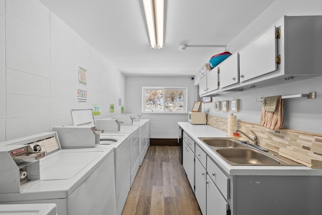 kitchen with sink, white cabinetry, light wood-type flooring, independent washer and dryer, and backsplash