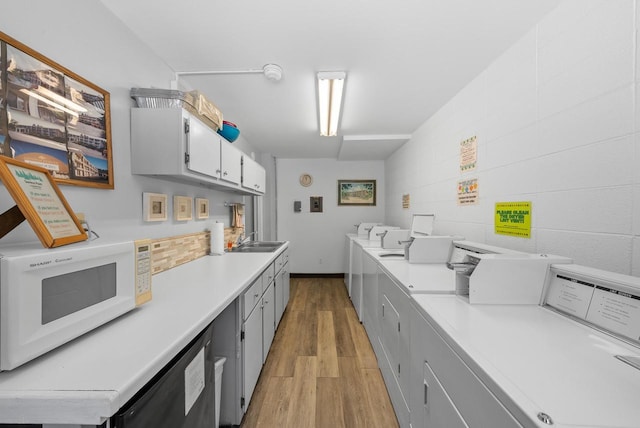 kitchen featuring sink, washer and clothes dryer, light hardwood / wood-style flooring, dishwasher, and gray cabinetry