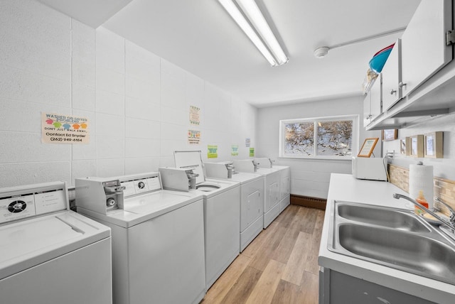 laundry area with sink, tile walls, light wood-type flooring, cabinets, and washer and clothes dryer