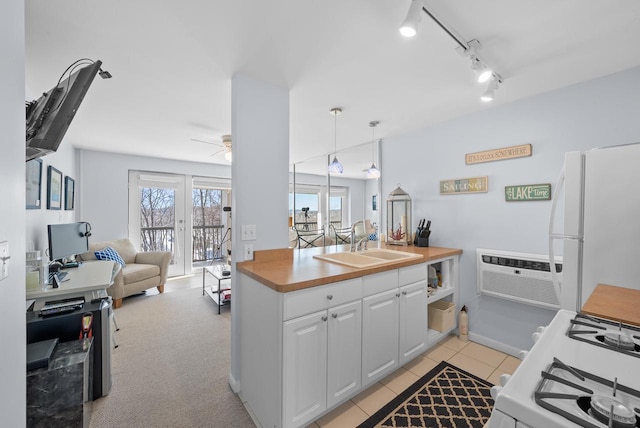 kitchen with pendant lighting, sink, white appliances, white cabinetry, and a wall mounted AC