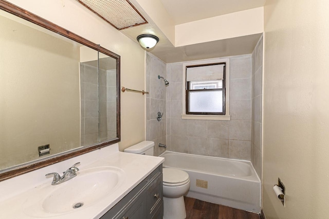 full bathroom with tiled shower / bath combo, vanity, wood-type flooring, and toilet