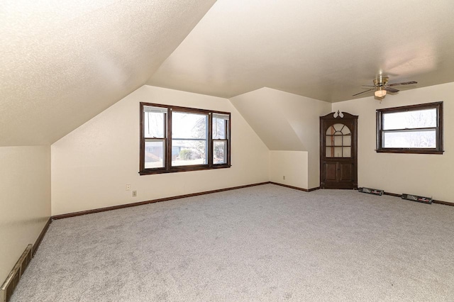 bonus room featuring light colored carpet, plenty of natural light, vaulted ceiling, and a textured ceiling