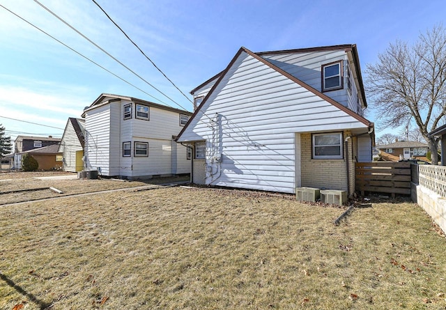 rear view of house featuring central AC unit and a lawn