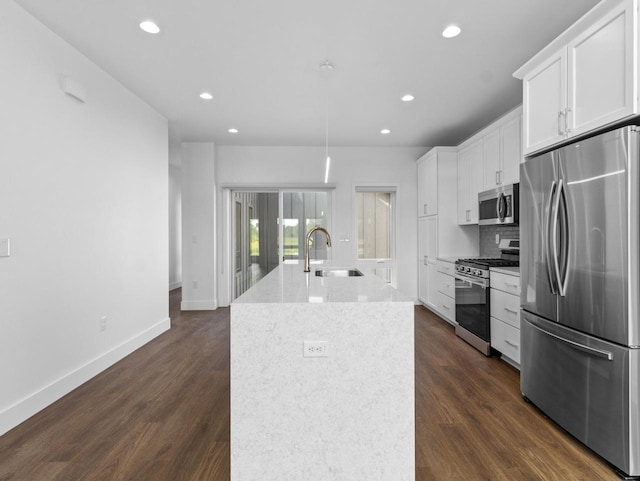 kitchen featuring white cabinetry, sink, stainless steel appliances, dark wood-type flooring, and a center island with sink