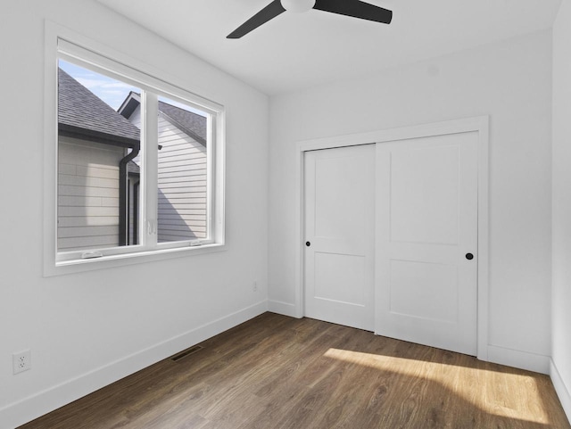 unfurnished bedroom featuring ceiling fan, dark hardwood / wood-style flooring, and a closet