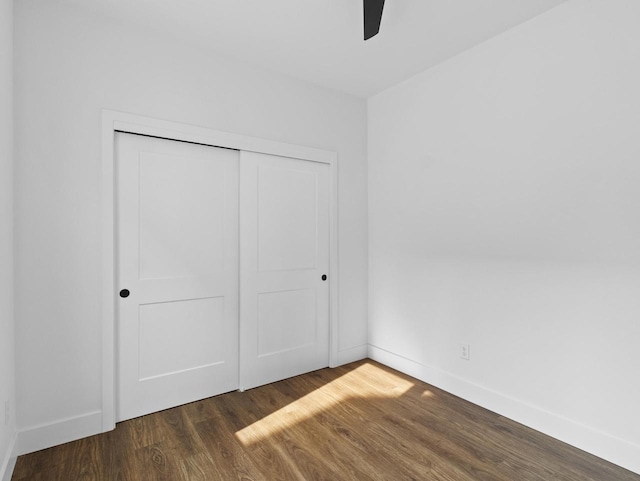 unfurnished bedroom with ceiling fan, dark hardwood / wood-style floors, and a closet