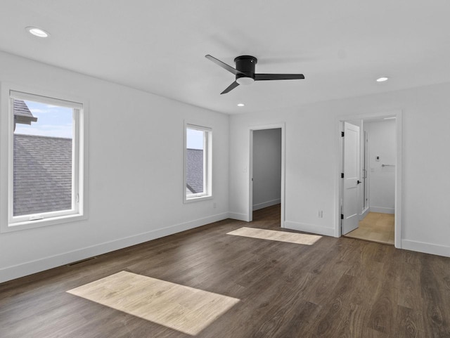 unfurnished bedroom with dark wood-type flooring, a walk in closet, and ceiling fan