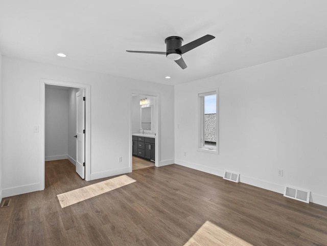 unfurnished bedroom with ensuite bathroom, sink, a walk in closet, dark hardwood / wood-style floors, and ceiling fan