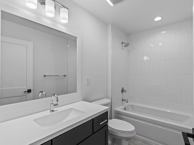 full bathroom featuring tiled shower / bath, vanity, and toilet