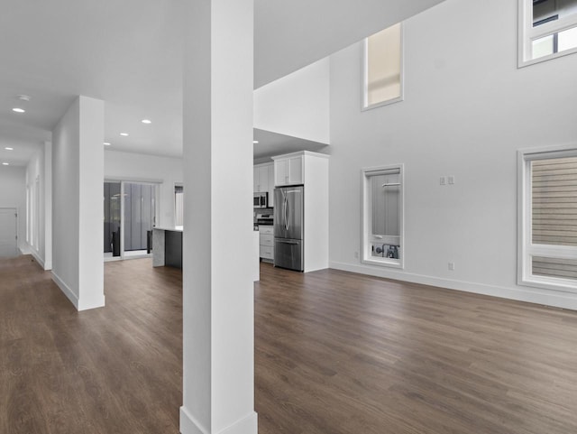 unfurnished living room featuring a high ceiling and dark wood-type flooring