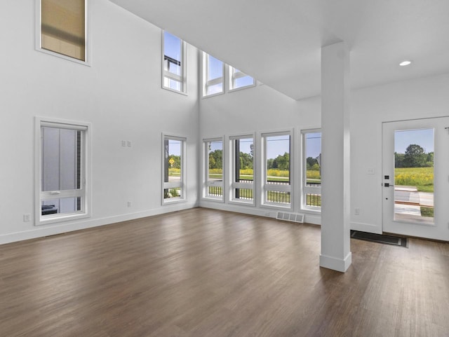 unfurnished living room featuring dark hardwood / wood-style floors and a towering ceiling