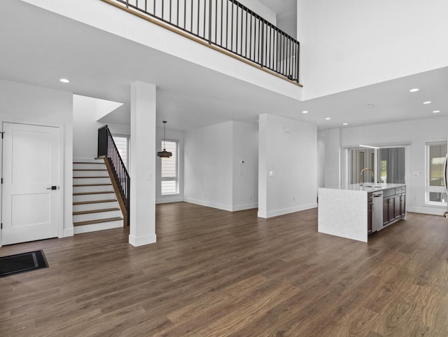 unfurnished living room with dark hardwood / wood-style floors, sink, and a high ceiling