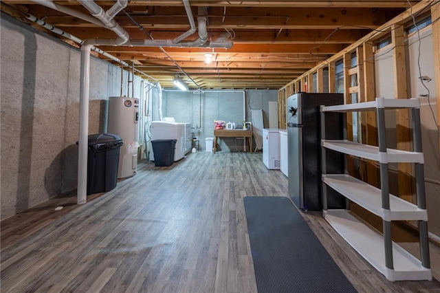 basement with independent washer and dryer, refrigerator, hardwood / wood-style floors, and water heater