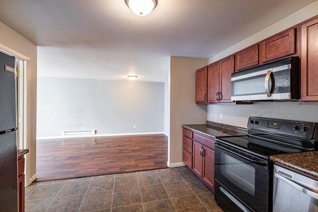 kitchen with a baseboard heating unit, dark stone countertops, and black appliances