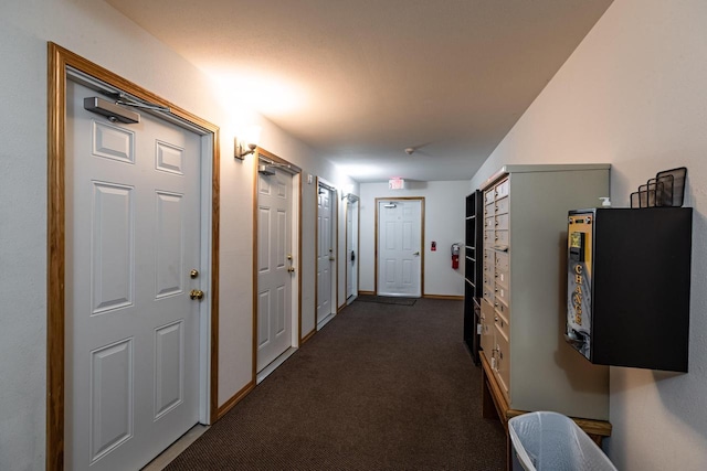 hall with mail boxes and dark colored carpet